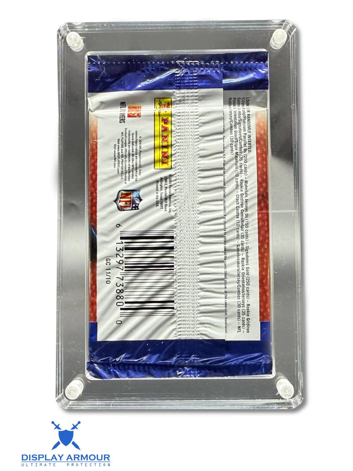 A sealed Panini trading card pack displayed inside a clear acrylic corner display case with white mounting dots, photographed on a white background. The pack is blue, white, and red, with a visible Panini logo and barcode.